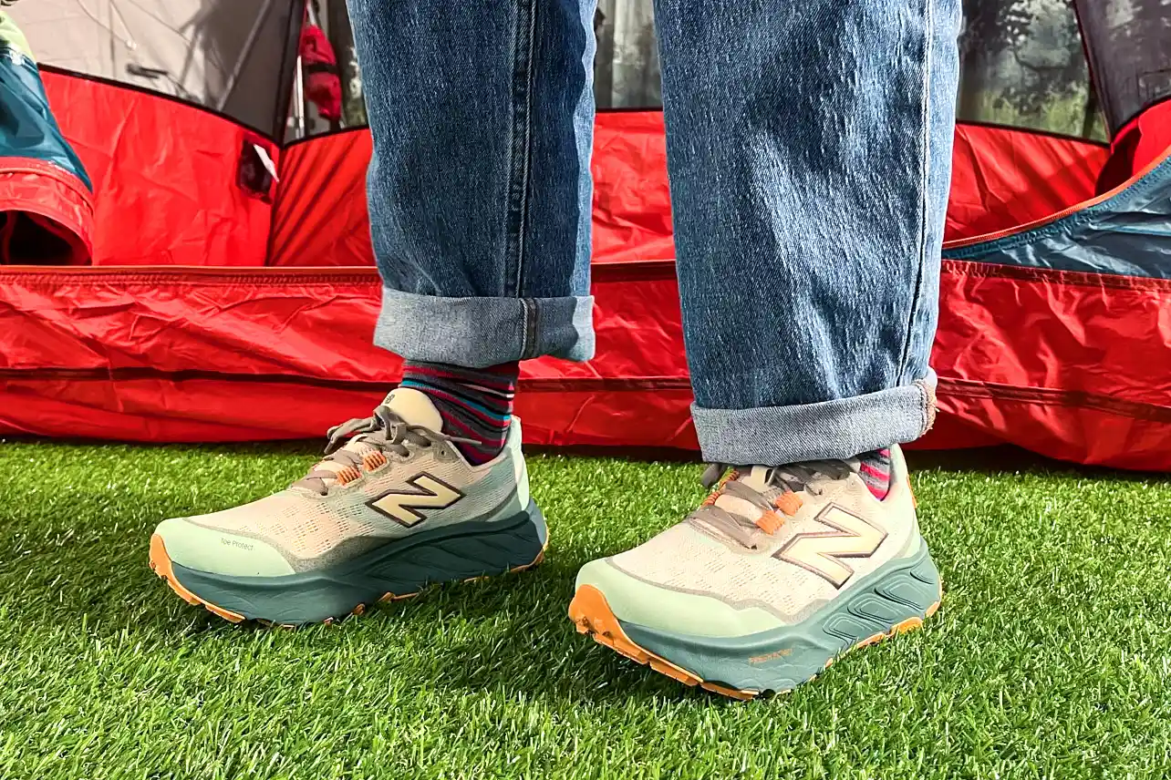 A person stands in grass while wearing the New Balance Women's Fresh Foam X Hierro v9 Running Shoes