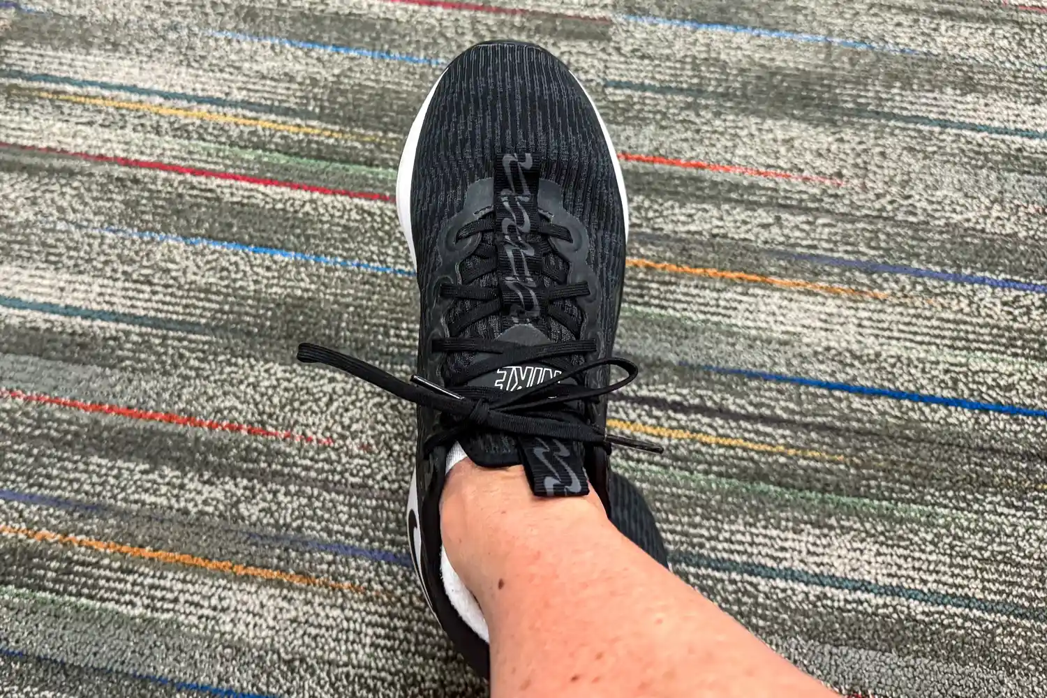 A person's foot wearing the Nike Motiva Women's Walking Shoe