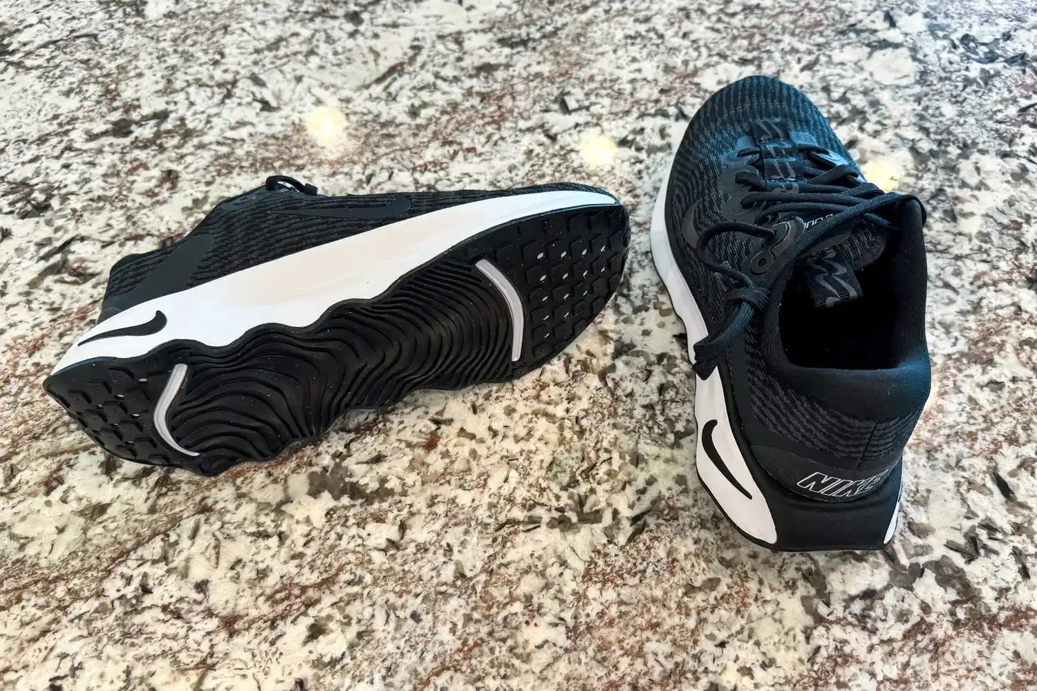A pair of Nike Motiva Women's Walking Shoes on a stone countertop