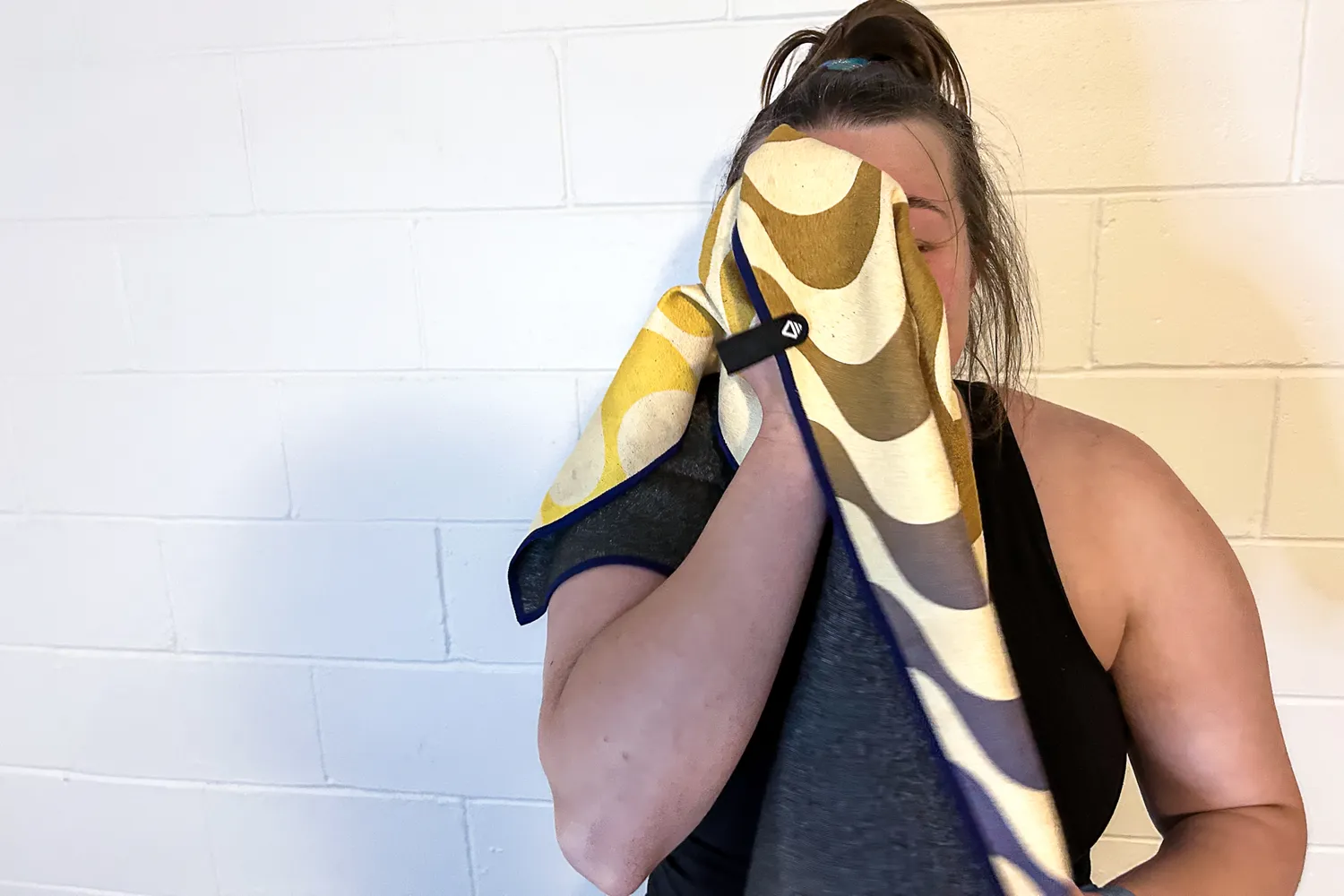 A person wipes their face using the Nomadix Fitness Towel