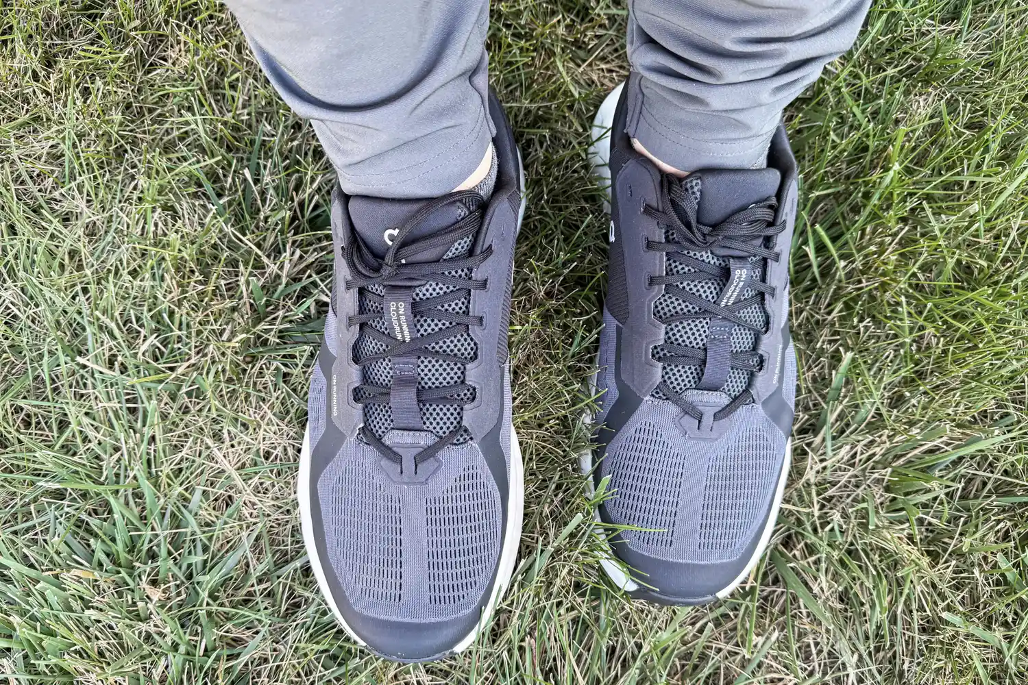 An overhead view of a person wearing the On Running Men's Cloudrunner 2 Wide Running Shoes in grass