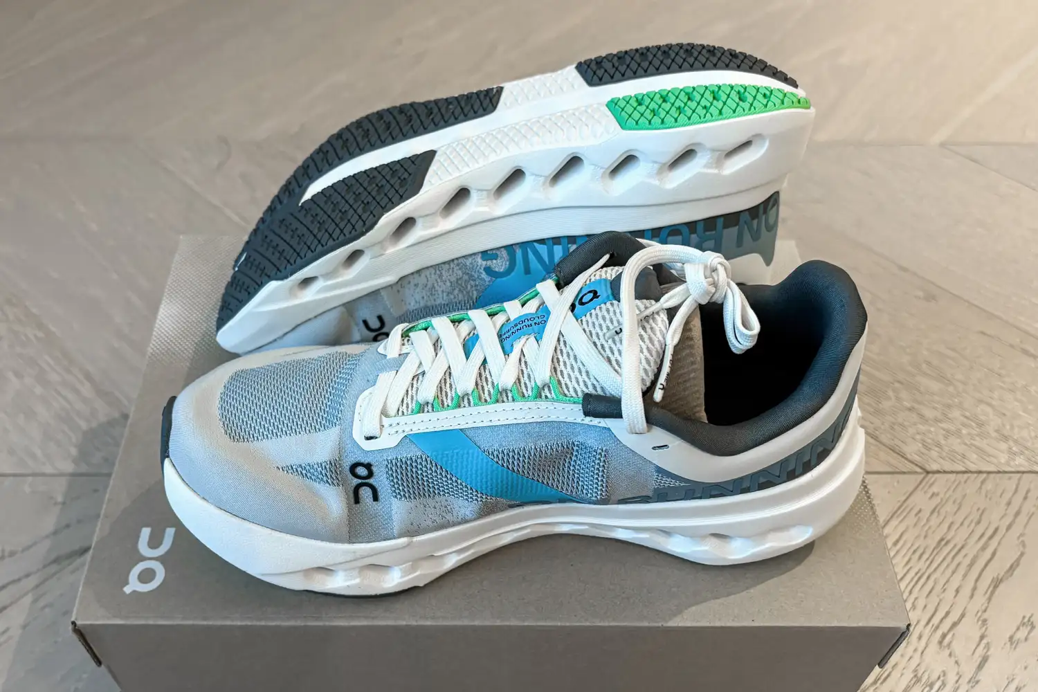 A pair of On Running Women's Cloudsurfer Next Wide Running Shoes on a branded shoebox