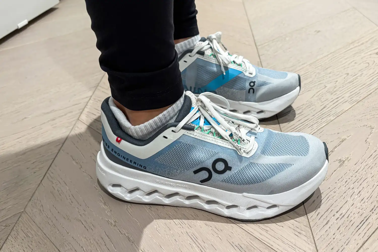 A side view of a person wearing the On Running Women's Cloudsurfer Next Wide Running Shoes