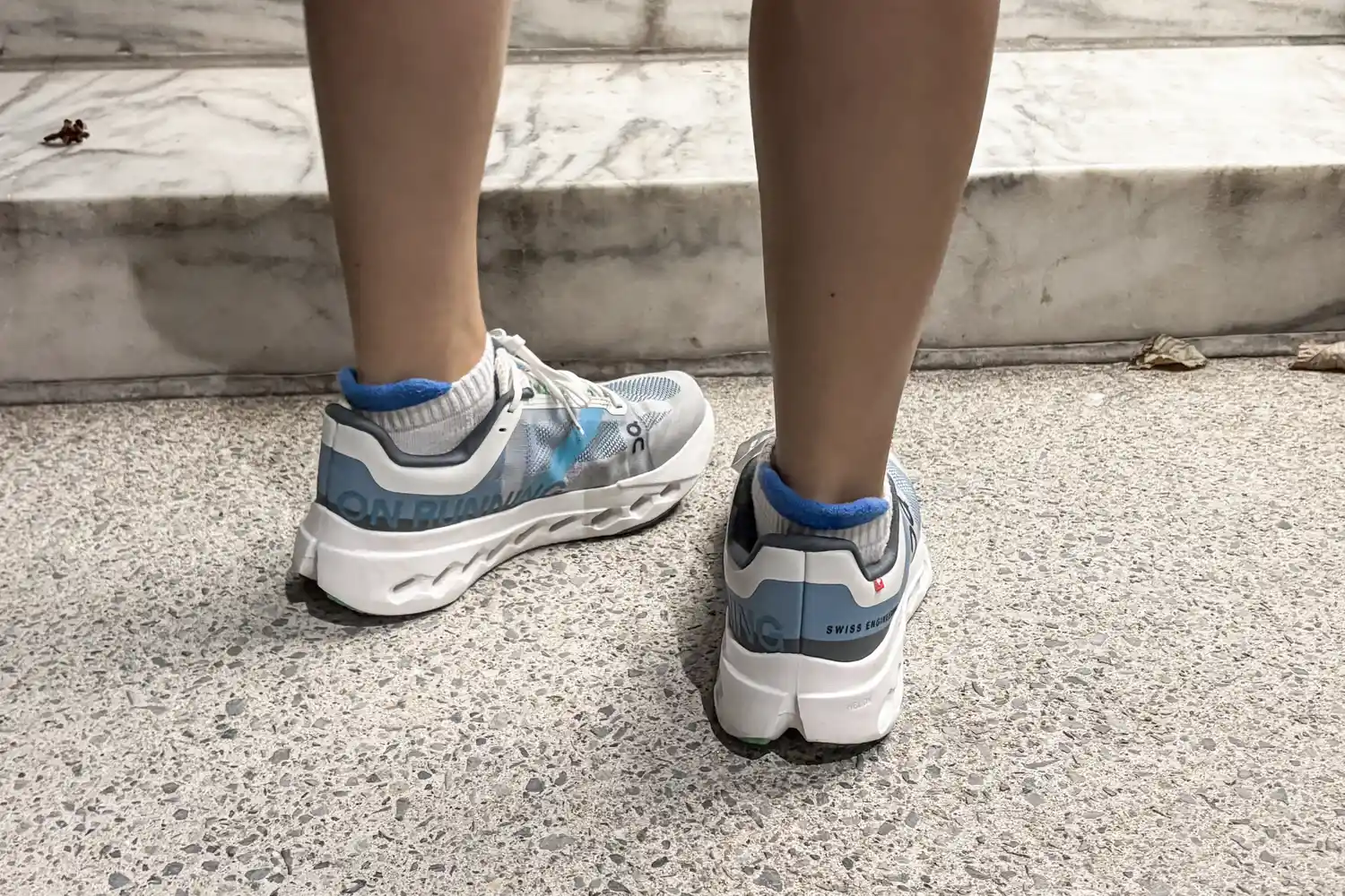The back of a person wearing the On Running Women's Cloudsurfer Next Wide Running Shoes