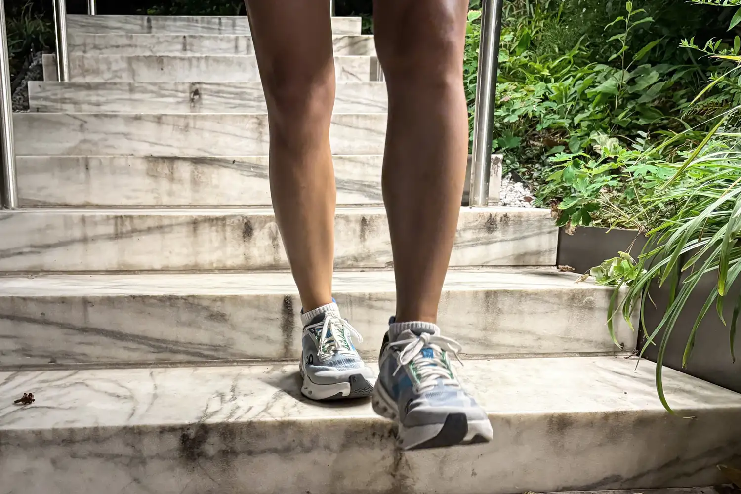 A person walks outside while wearing the On Running Women's Cloudsurfer Next Wide Running Shoes