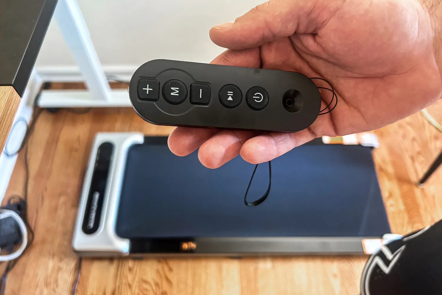 A person holds the remote control for the Orinar 3-in-1 Walking Pad