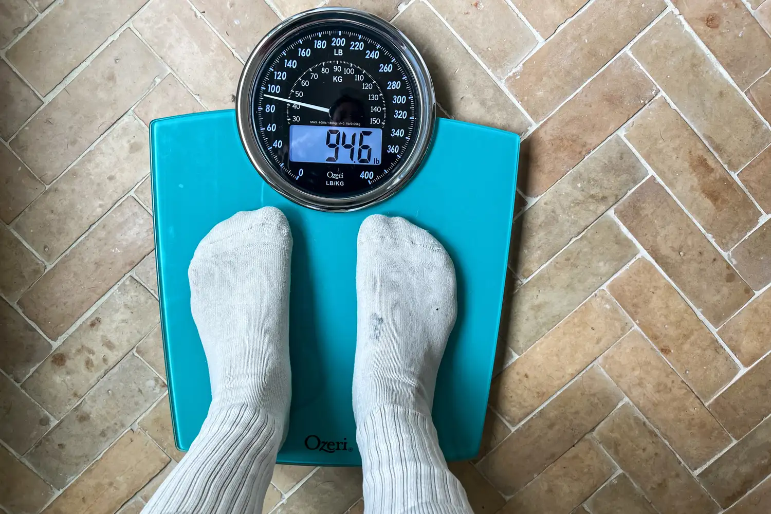 A person stands on the Ozeri Rev 400 lbs Bathroom Scale in socks