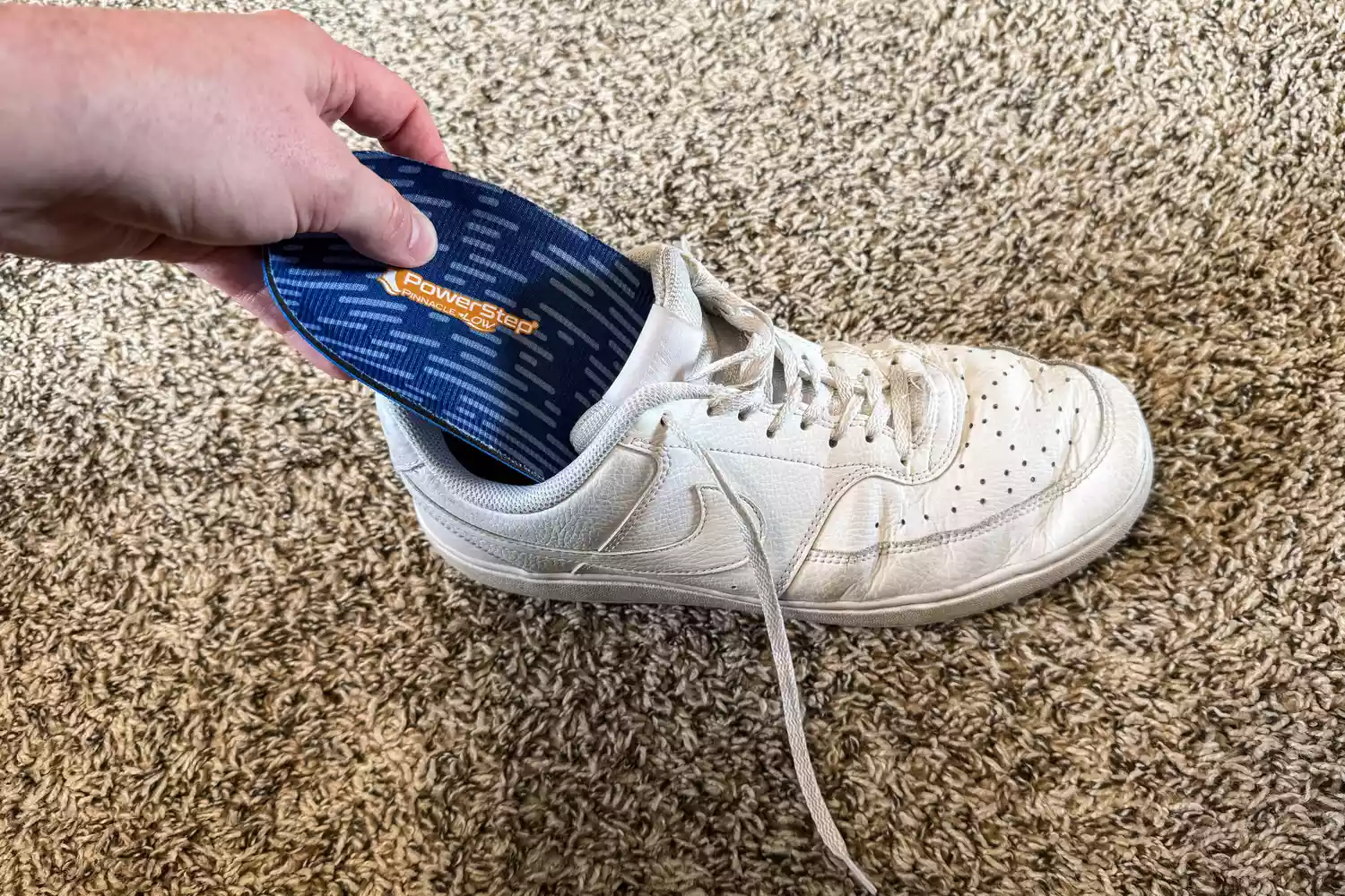 A person places the PowerStep Pinnacle Low Insole into a sneaker