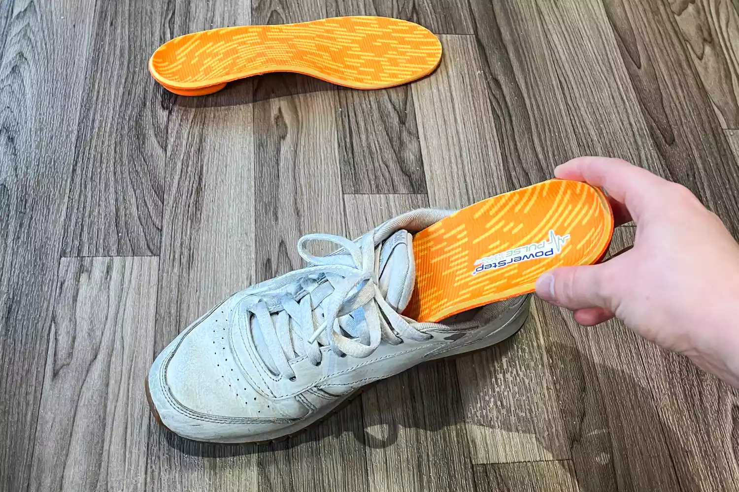 A person places a PowerStep PULSE Maxx Insole into a sneaker