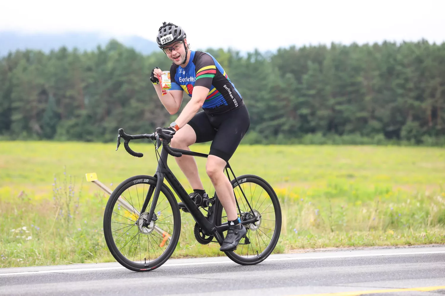 A person holds up a packet of Probar BOLT Organic Energy Chews while riding a bike