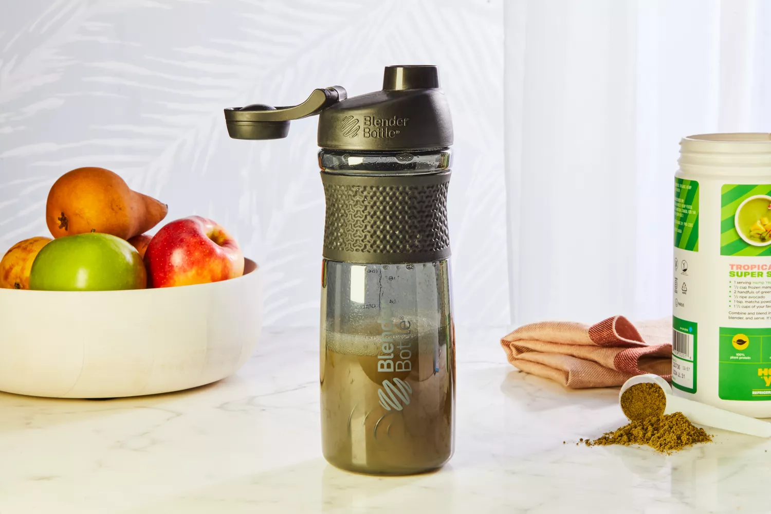 BlenderBottle SportMixer Tritan Grip Shaker Bottle displayed on counter with protein powder and fruit