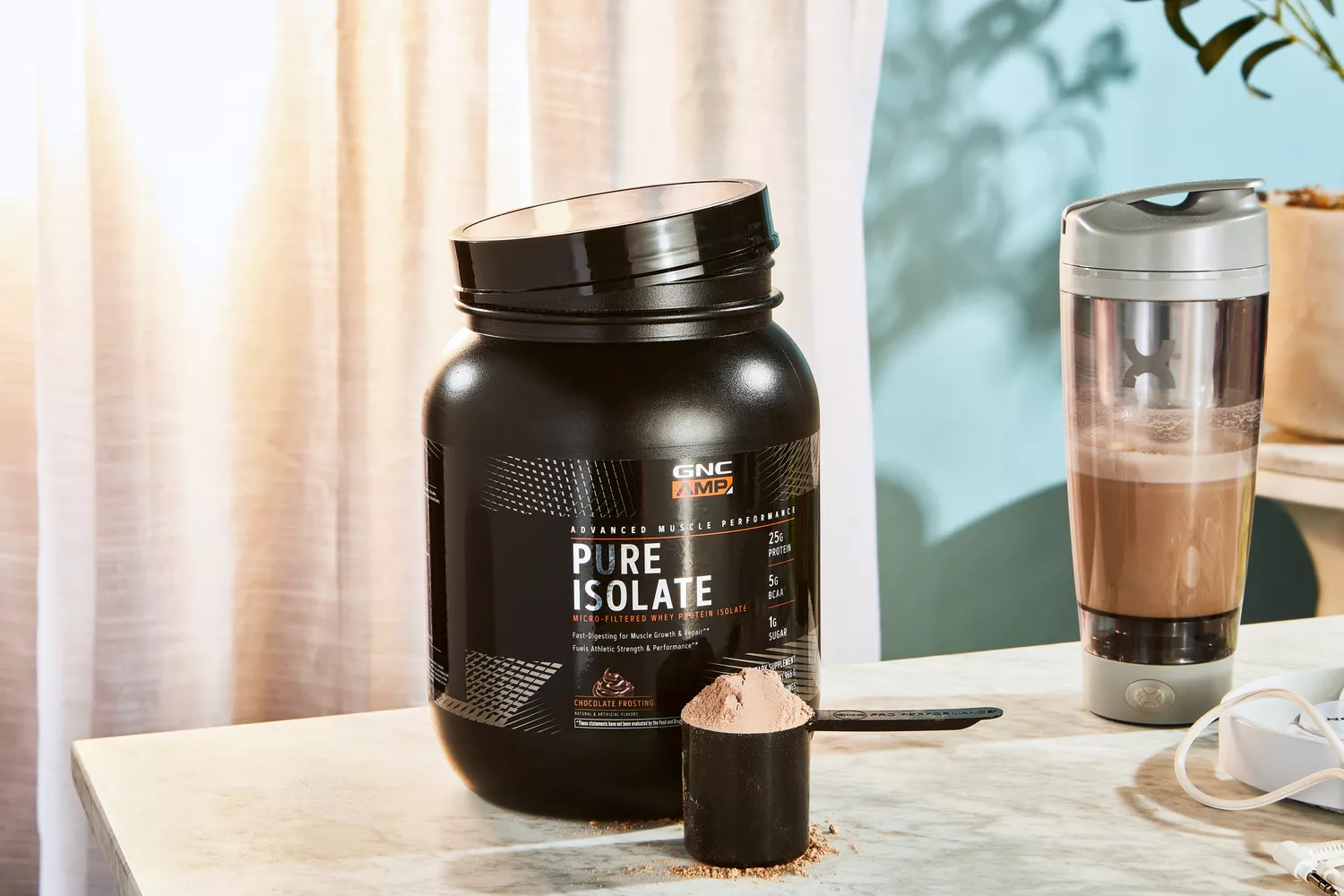 GNC AMP Pure Isolate Whey Protein powder in a scoop next to a jar and shaker bottle