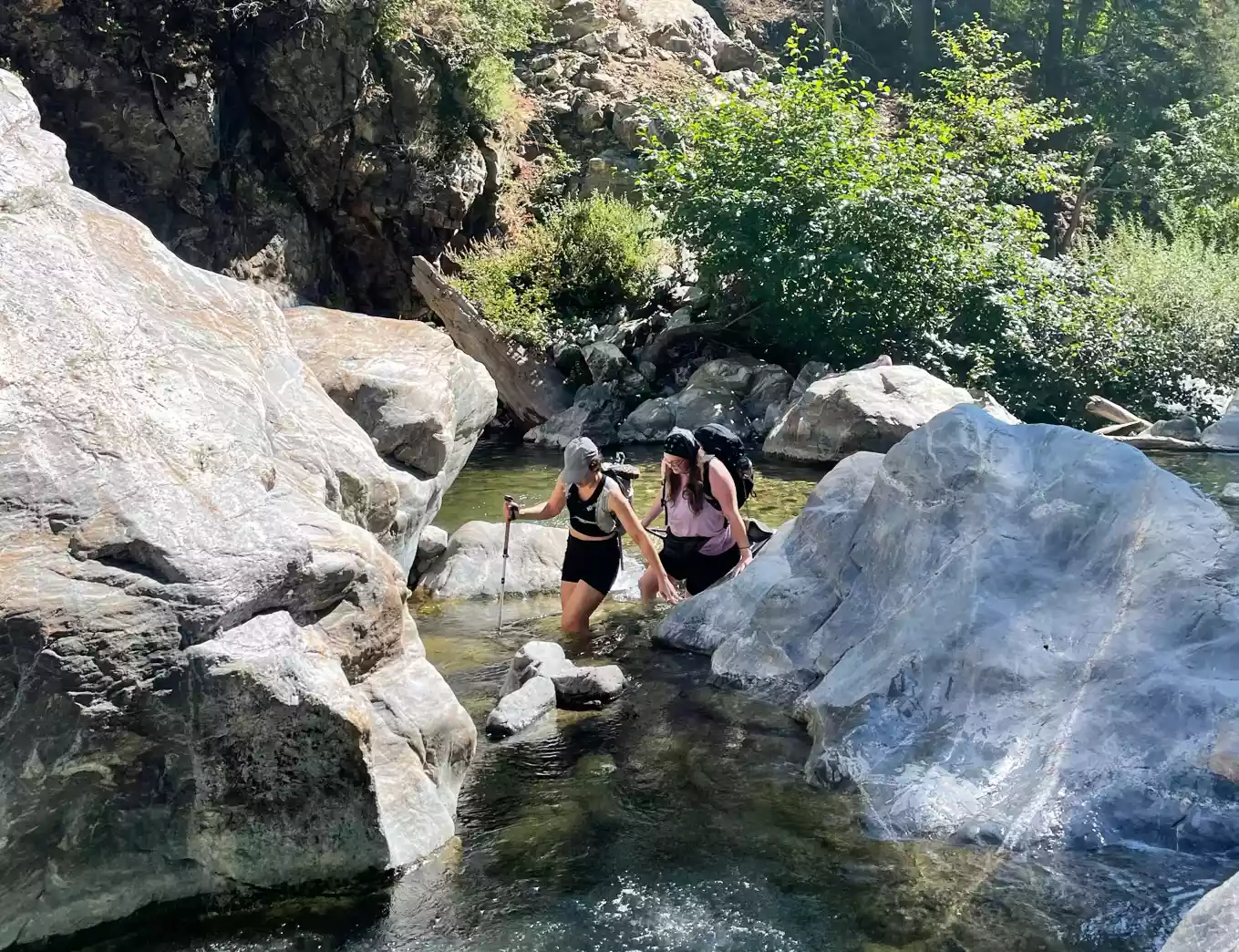 Two people walking through water with Leki Cressida FX Carbon AS Trekking Poles