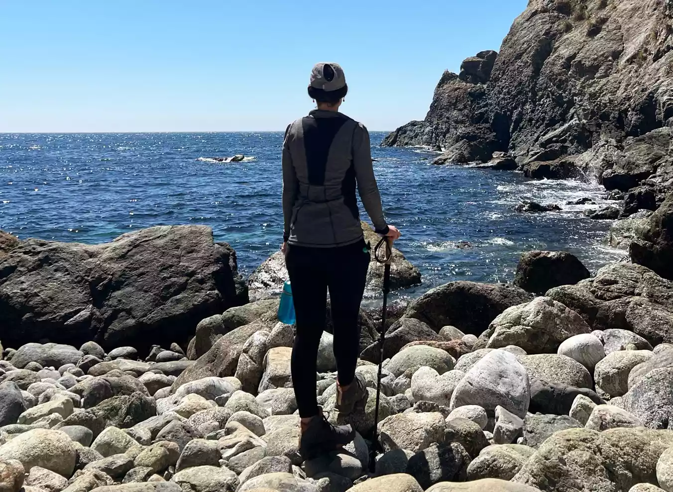 Person standing on rocks in front of water holding Leki Cressida FX Carbon AS Trekking Poles