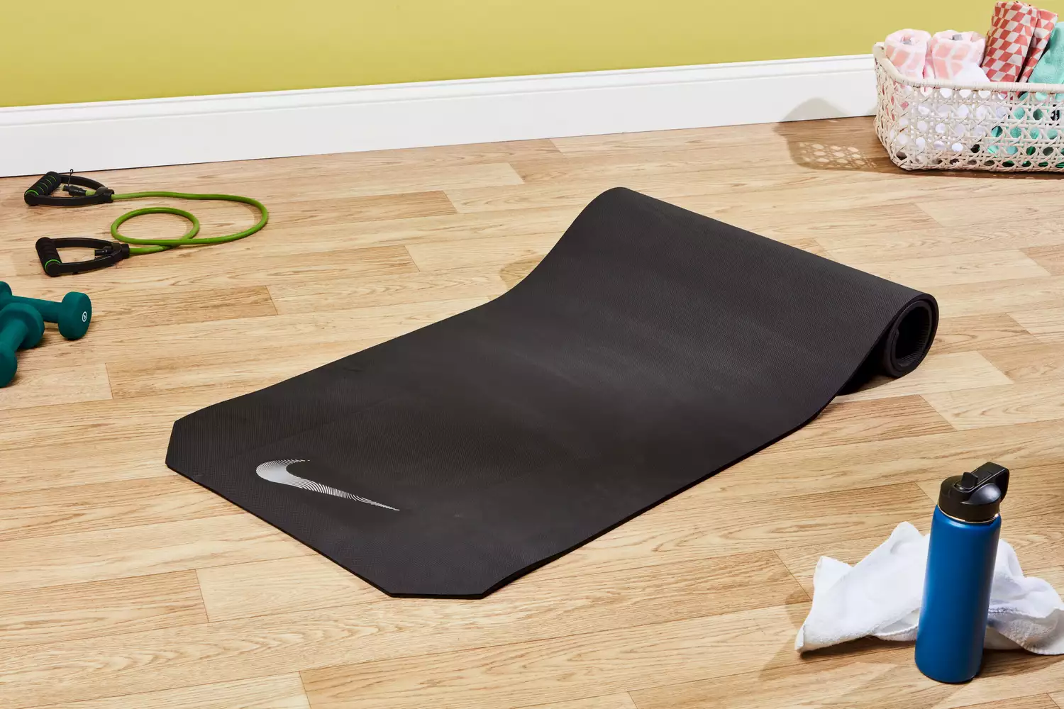 A half-rolled Nike Training Mat 2.0 surrounded by gym accessories