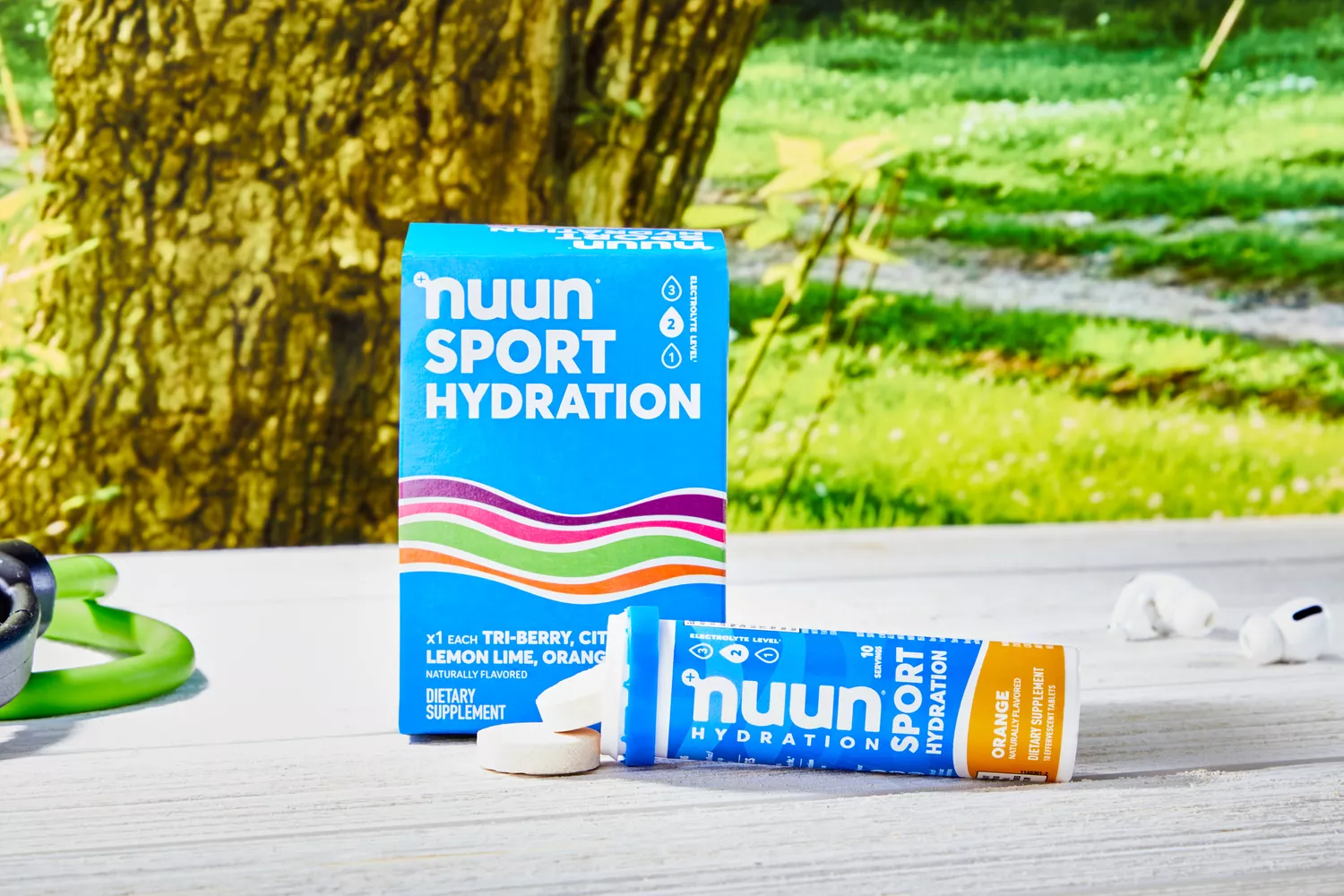 A Nuun Sport Electrolyte Drink Tablets box and container with tablets spilling out onto a wooden table