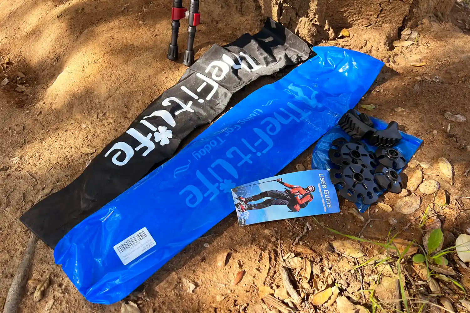 Hiking accessories on the ground including trekking poles a user manual and components