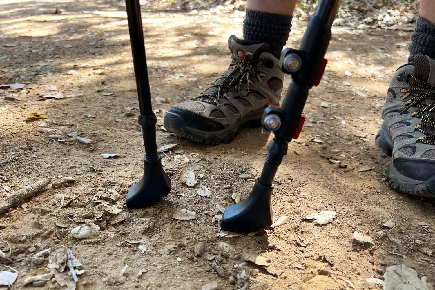 Hiking boots and walking poles on a dirt trail
