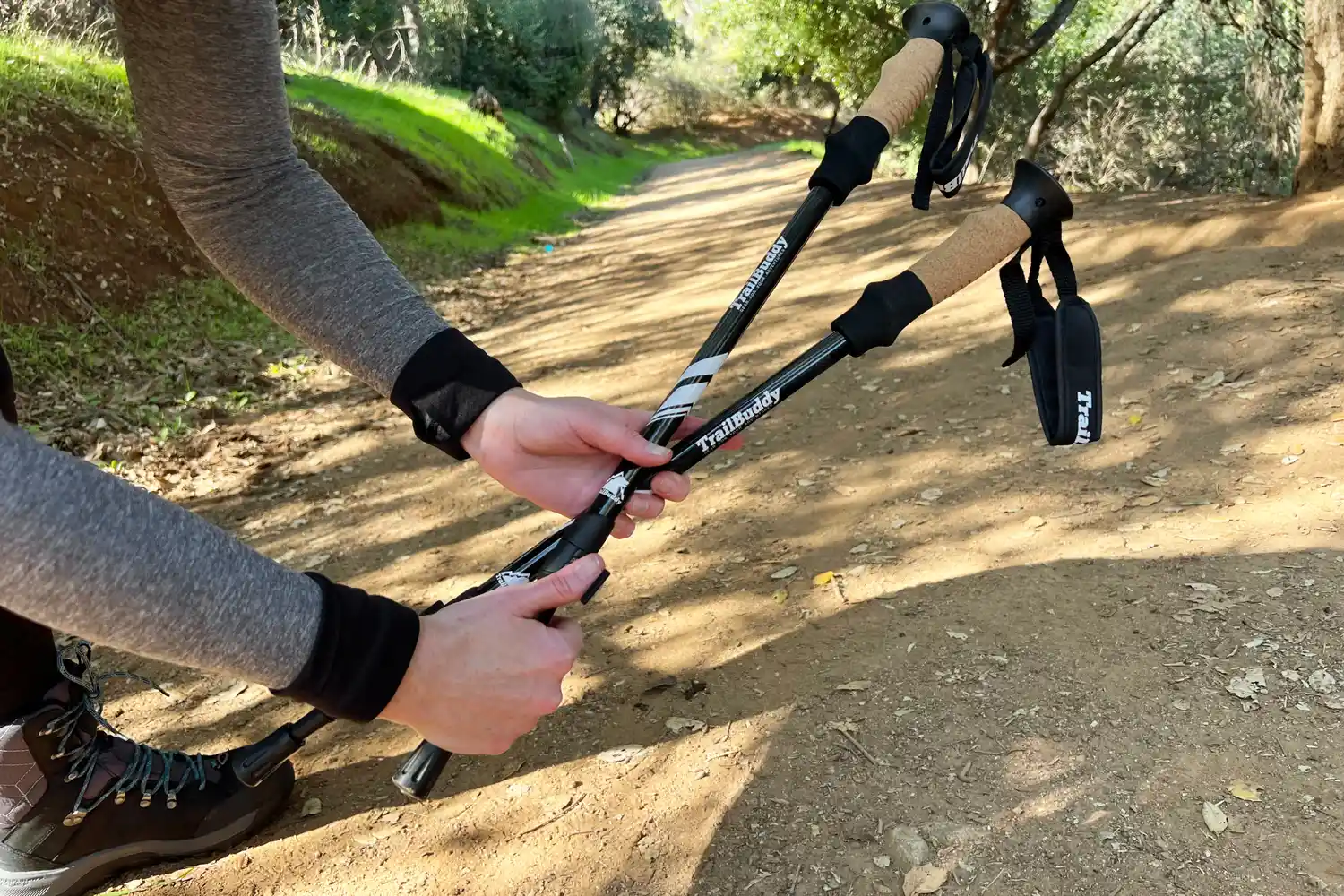 Hands adjusting hiking poles on a forest trail