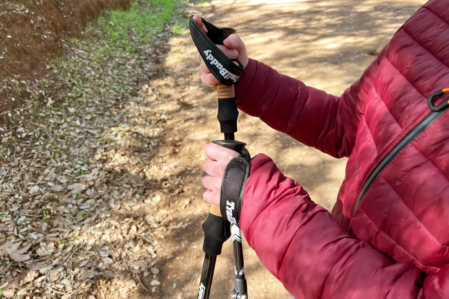 Person holding trekking poles on a dirt trail