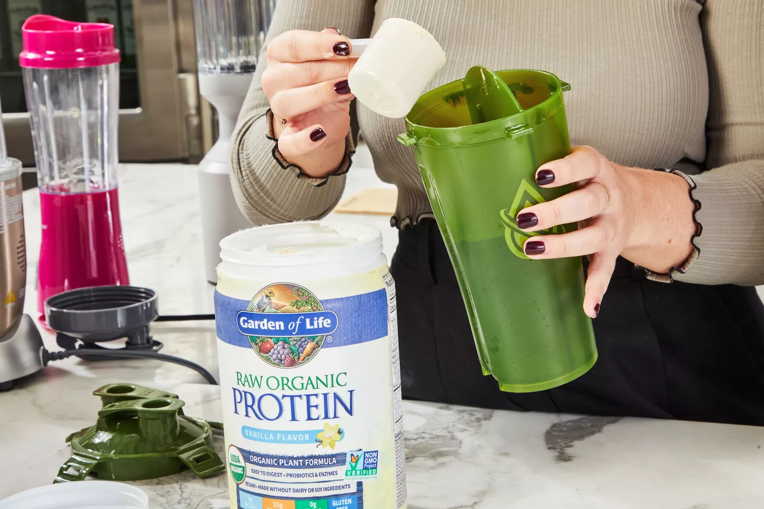 Person pouring scoop of Garden of Life Raw Organic Vanilla Protein Powder into shaker bottle