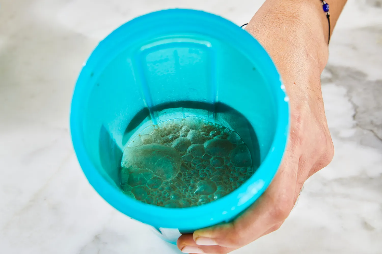A hand holding a blender bottle with a protein shake inside