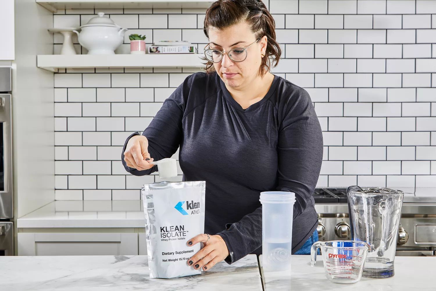 A person removes a scoop of Klean Athlete Klean Isolate Protein Powder from the bag