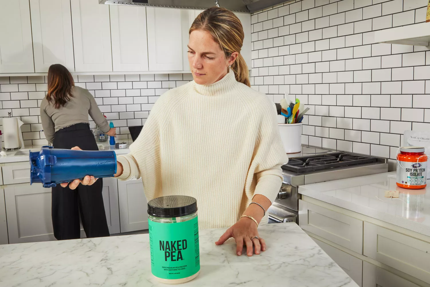 Person holding shaker next to jar of NAKED nutrition NAKED PEA 1LB Pea Protein Isolate