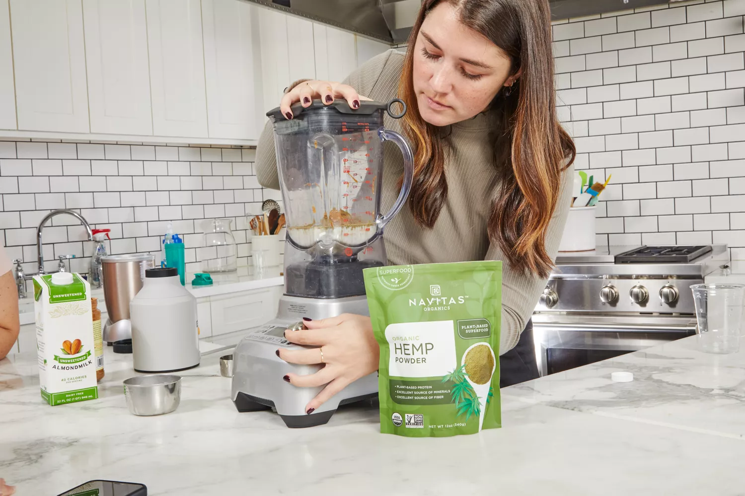 A person using a blender next to Navitas Organic Hemp Powder