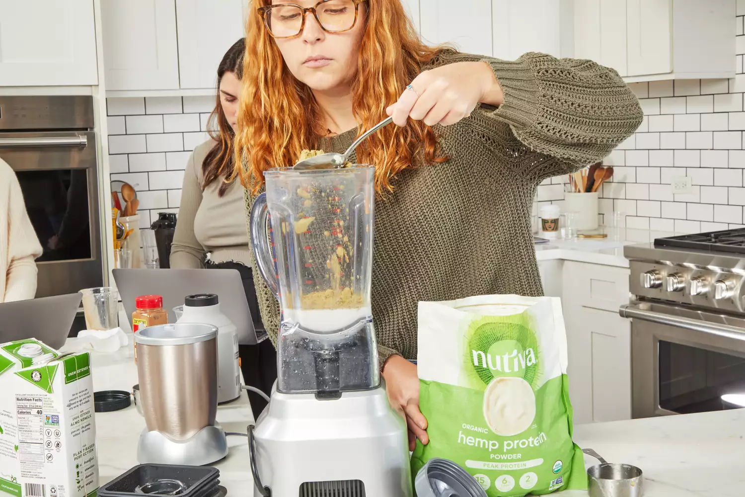  A person adding powder into a blender next to Nutiva Hemp Seed Protein Powder package