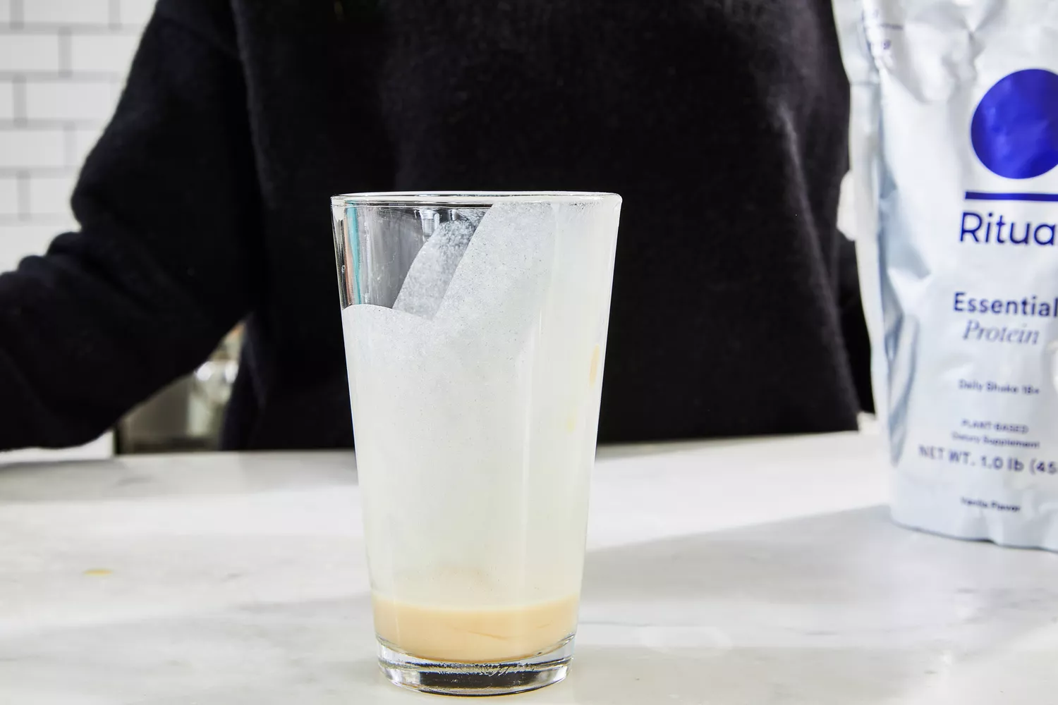 A glass of Ritual Essential Protein Daily Shake Protein Powder