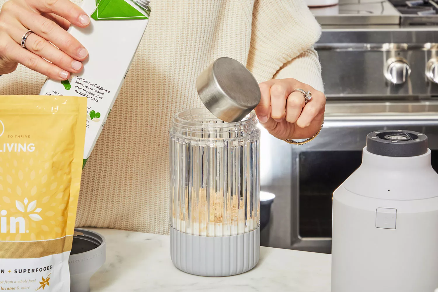 Hands using measuring cup to add milk to blender next to Sprout Living Epic Protein Vanilla Lucuma
