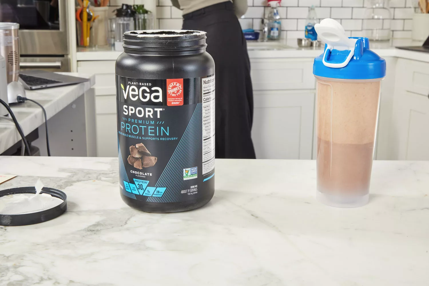 Vega Sport Premium Protein on marble counter next to half full protein shaker