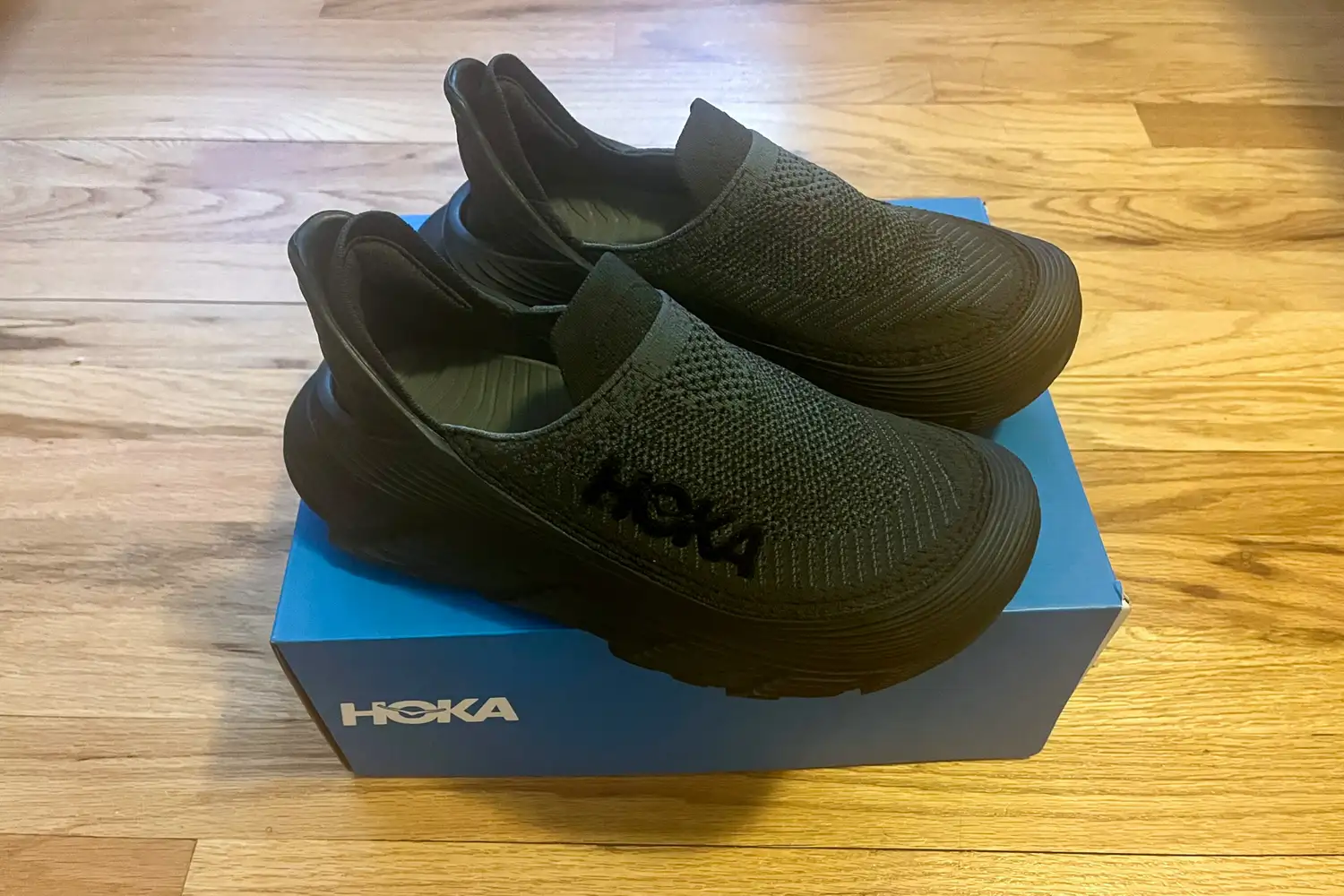 The Hoka Restore TC Recovery Shoes on top of their box