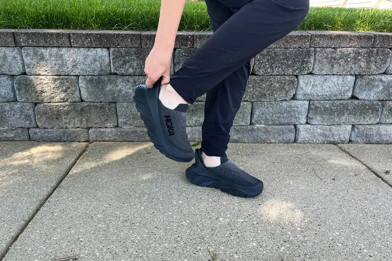 A person fixing the Hoka Restore TC Recovery Shoe on their foot