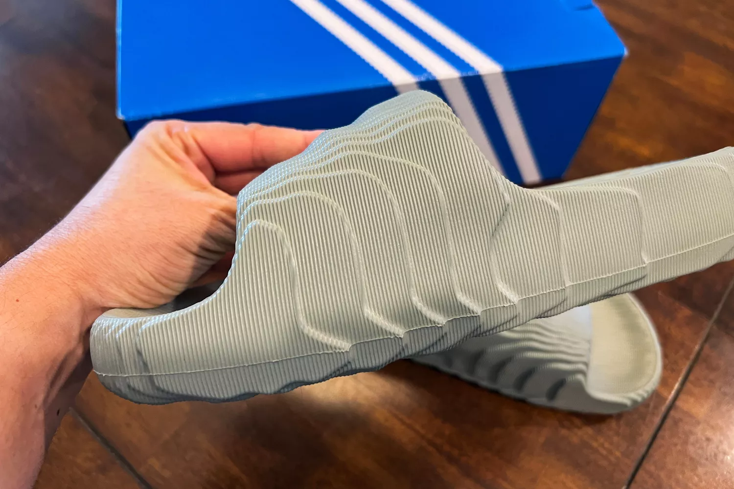 A person holds up the Adidas Adilette 22 Slide