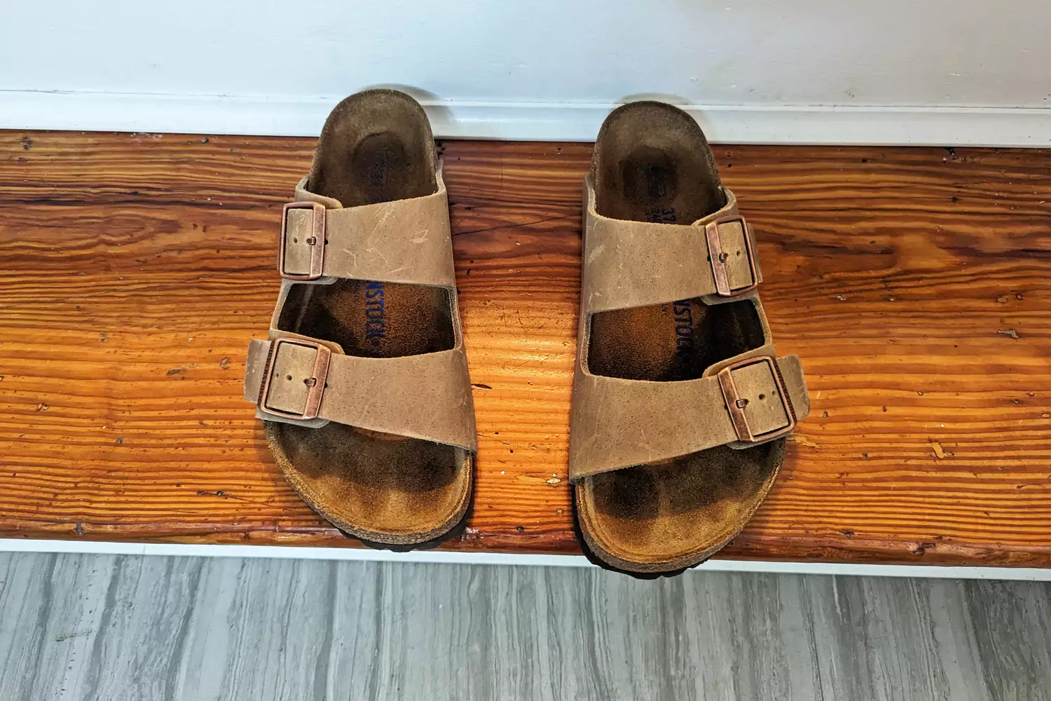 A pair of Birkenstock Women's Arizona Soft Footbed Sandal on a wooden floor