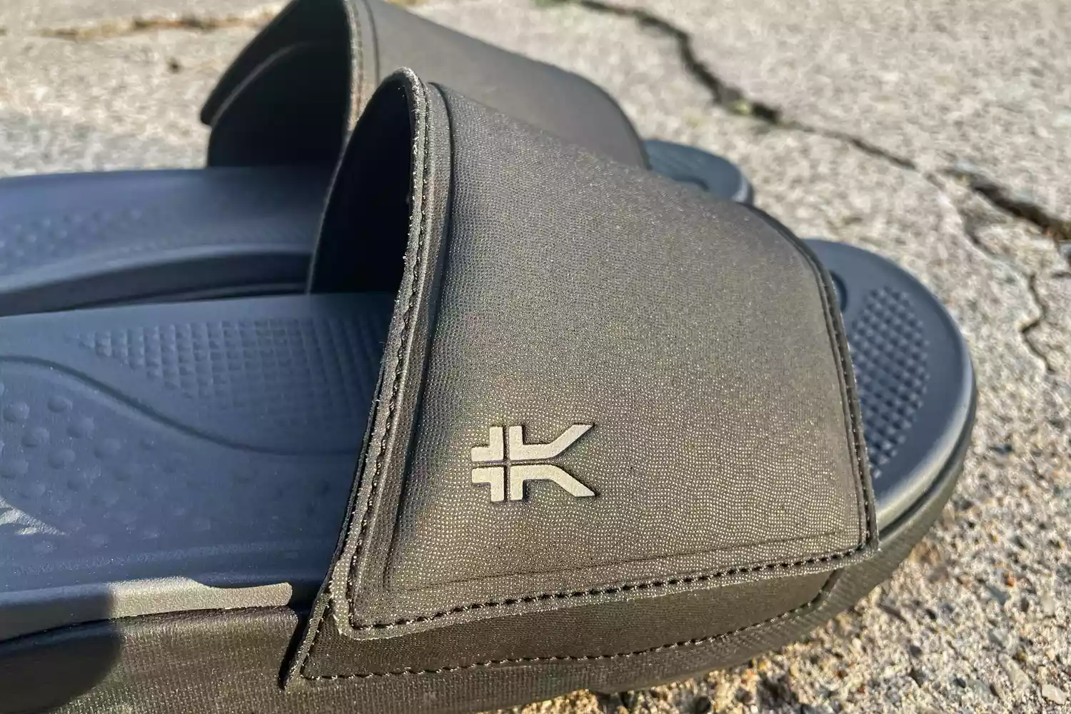 The logo on the side of the Kuru Men's Moment Slide Sandal