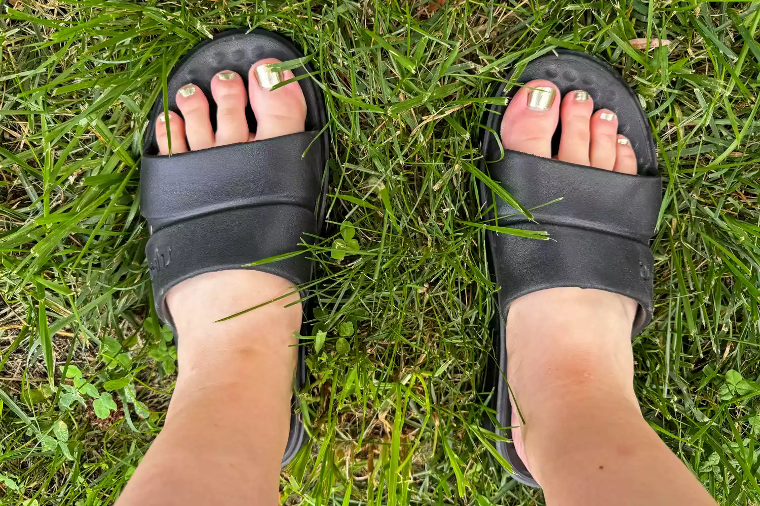 An overhead view of a person wearing the Ryka Women's Restore Recovery Slides in grass