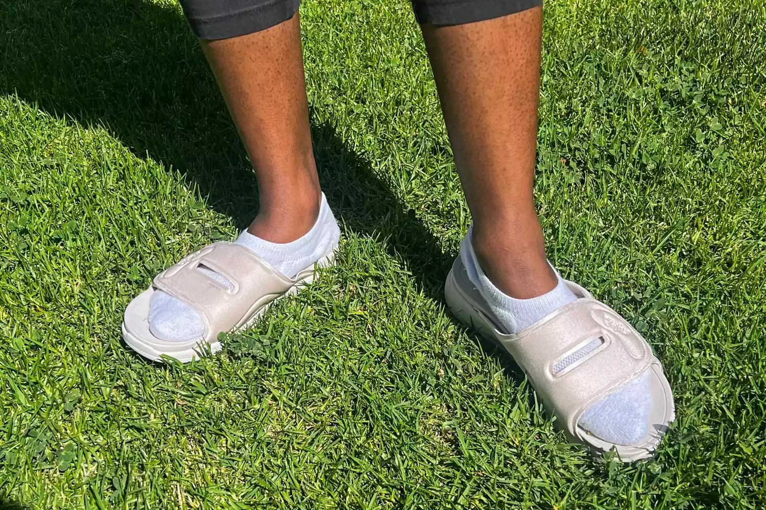 A person wears the Ryka Women's Tao Recovery Slide Sandals in grass
