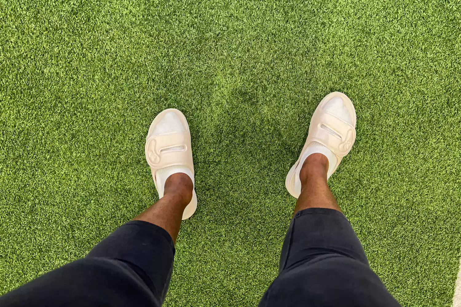 A person stands in grass while wearing the Ryka Women's Tao Recovery Slide Sandal