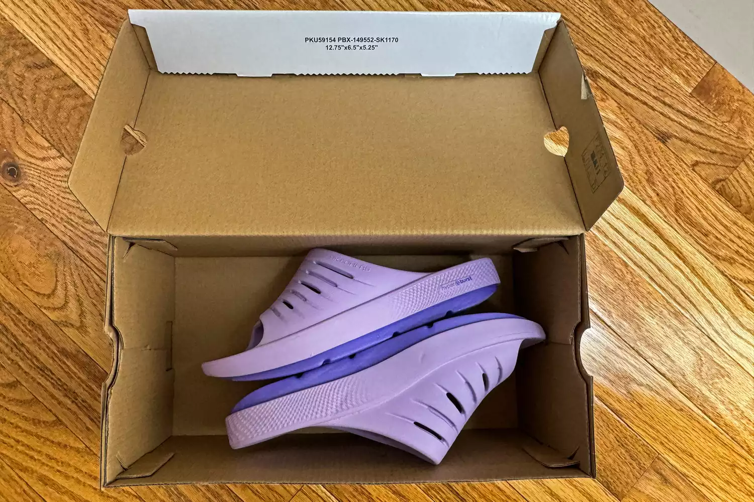 A pair of Skechers Women's GO RECOVER Refresh Slides in a shoebox