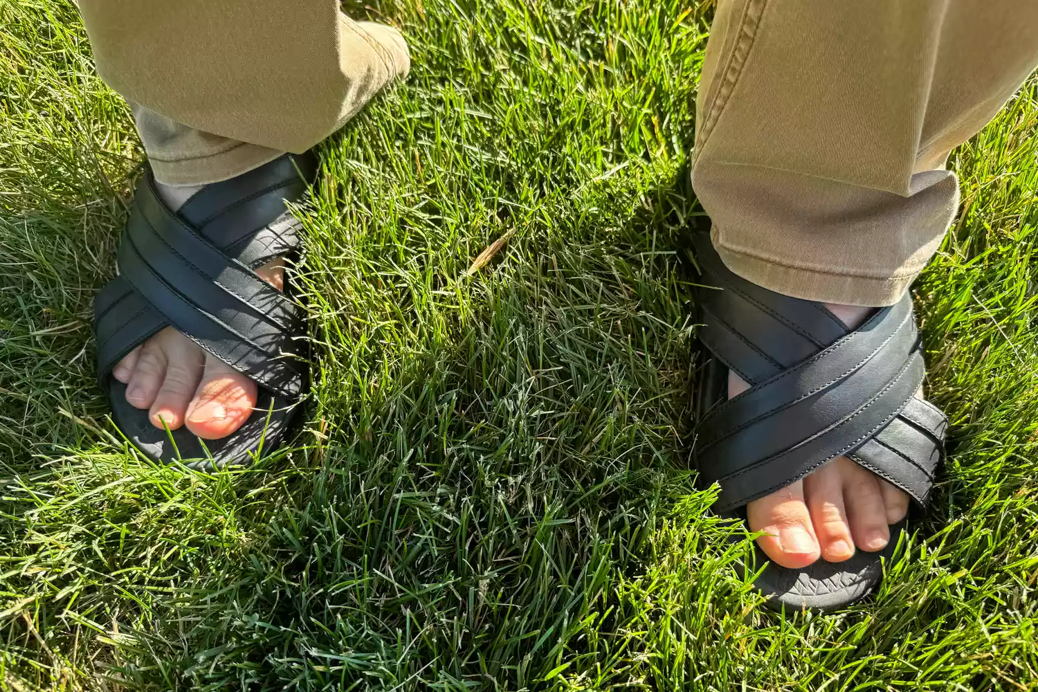 A person stands in grass while wearing the Vionic Men's Tide Slide Sandals