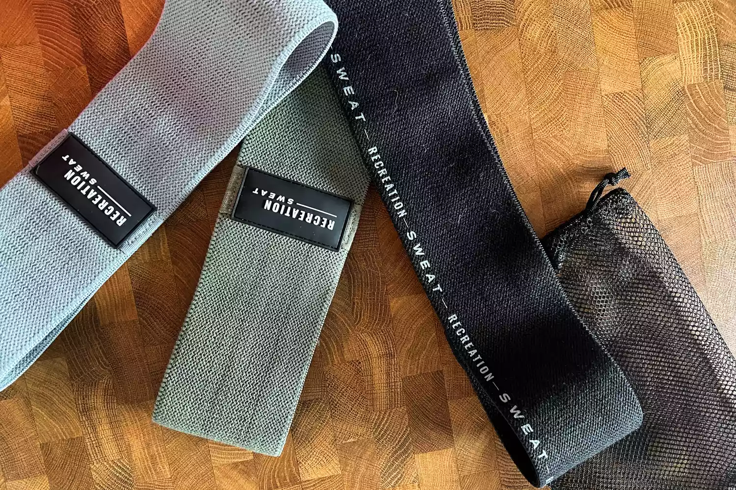 The Recreation Sweat Resistance Bands 2.0 and mesh storage bag on a wooden surface
