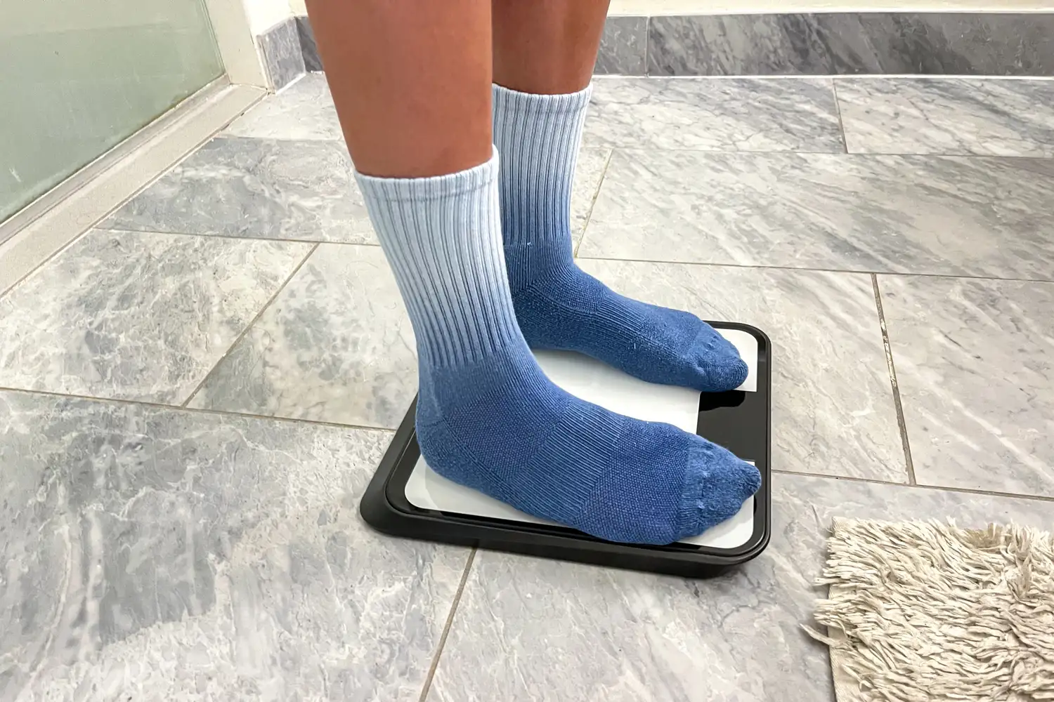 A person stands on the Renpho R-MSB02 Elis Chroma Aspire Smart Scale on a tile floor
