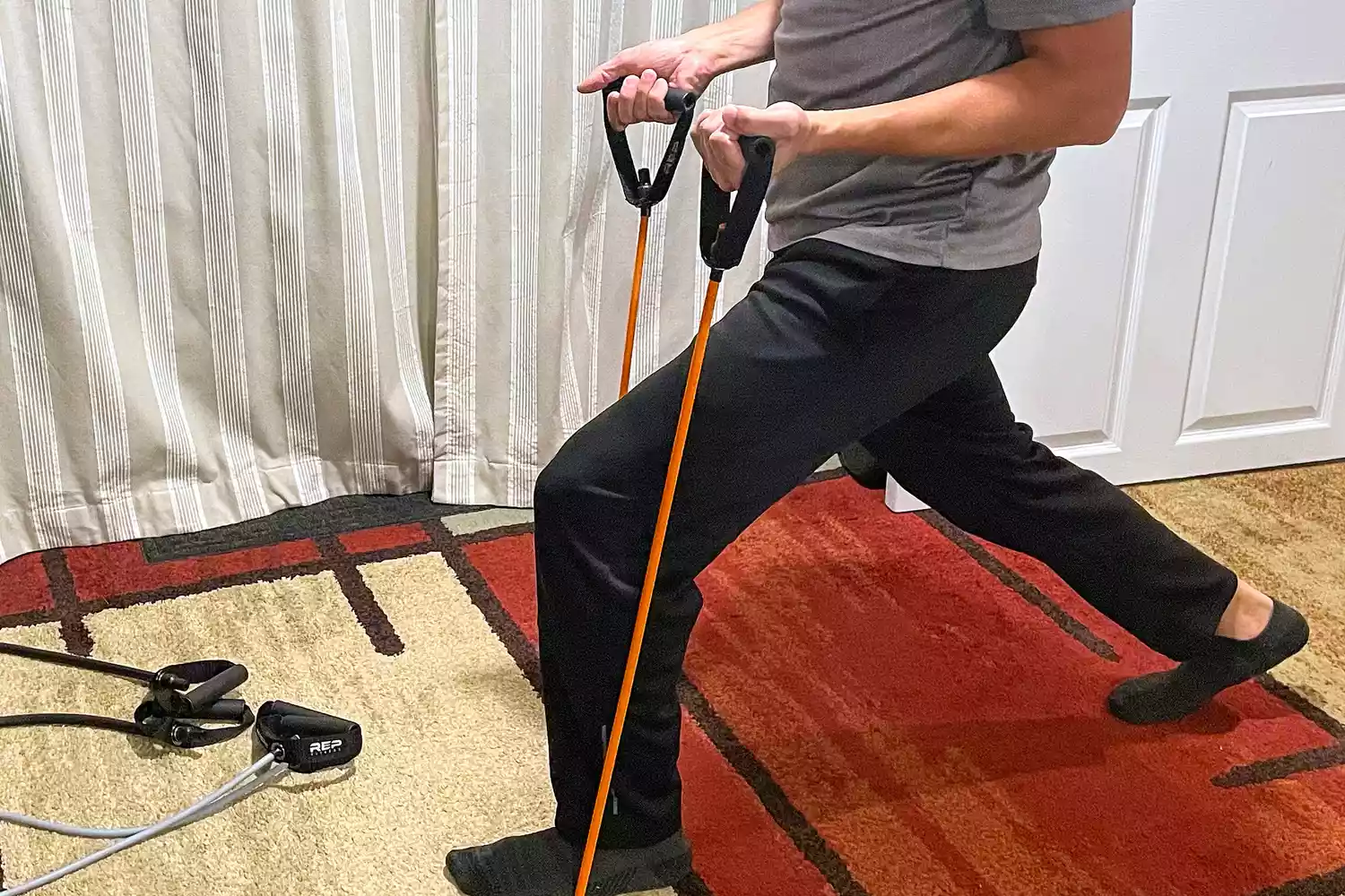A person lunging while using the Rep Fitness Tube Resistance Bands with Handles