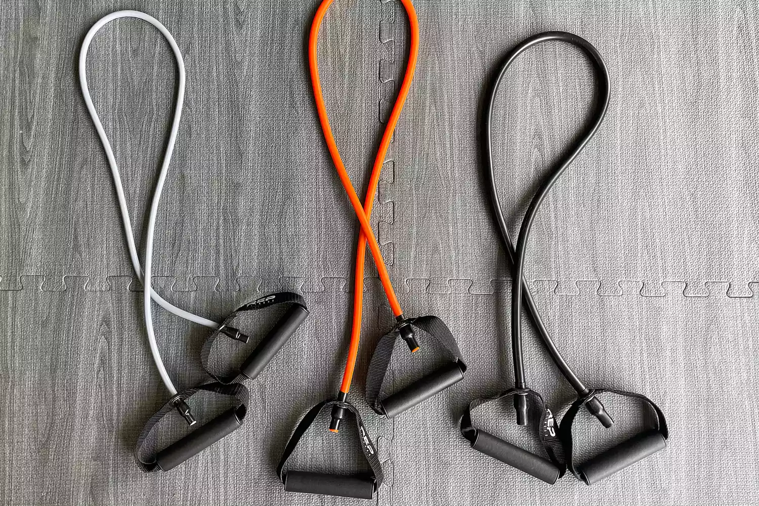 Three Rep Fitness Tube Resistance Bands with Handle on a gray floor