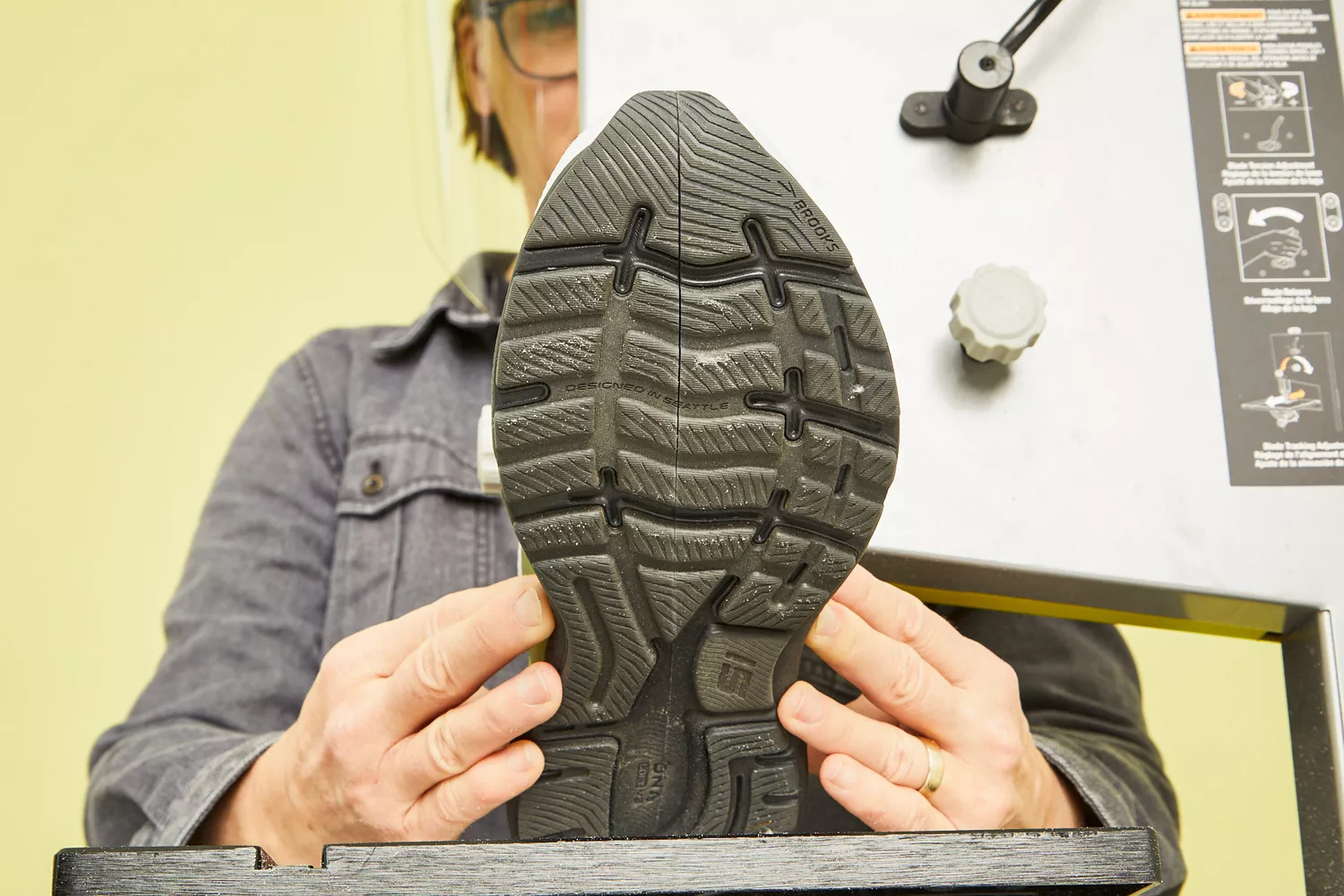 A person cutting the Brooks Men's Ghost 15 Running Shoes in half