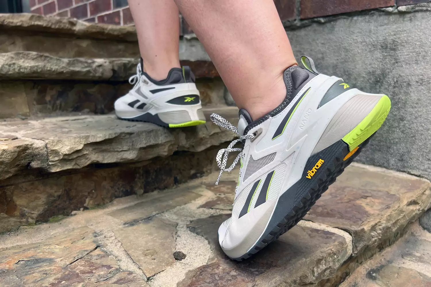 A close-up of a person wearing Reebok Nano X3 Adventure Training Shoes while climbing stairs