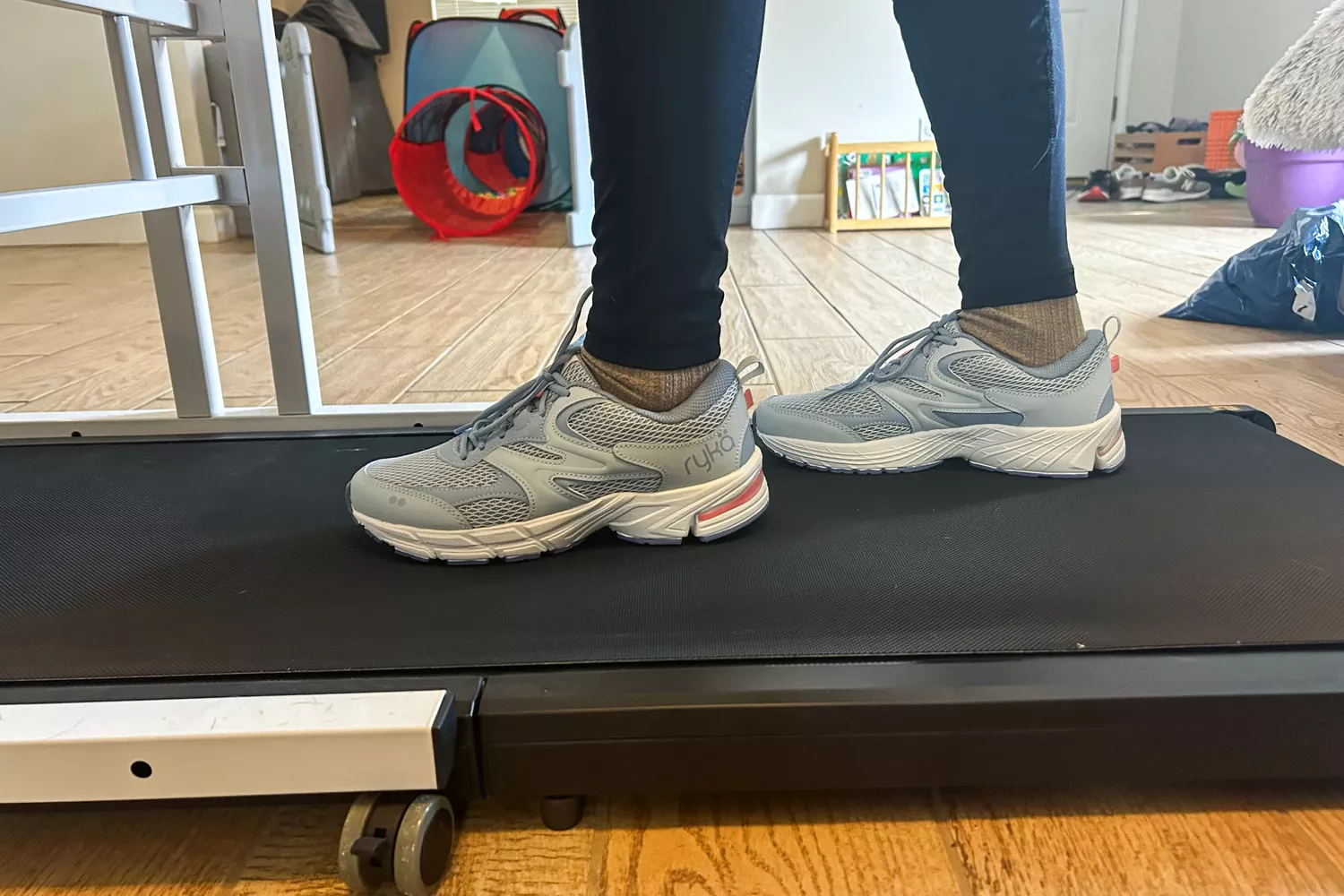 A side view of a person wearing the Ryka Women's Invoke Walking Shoes on a treadmill